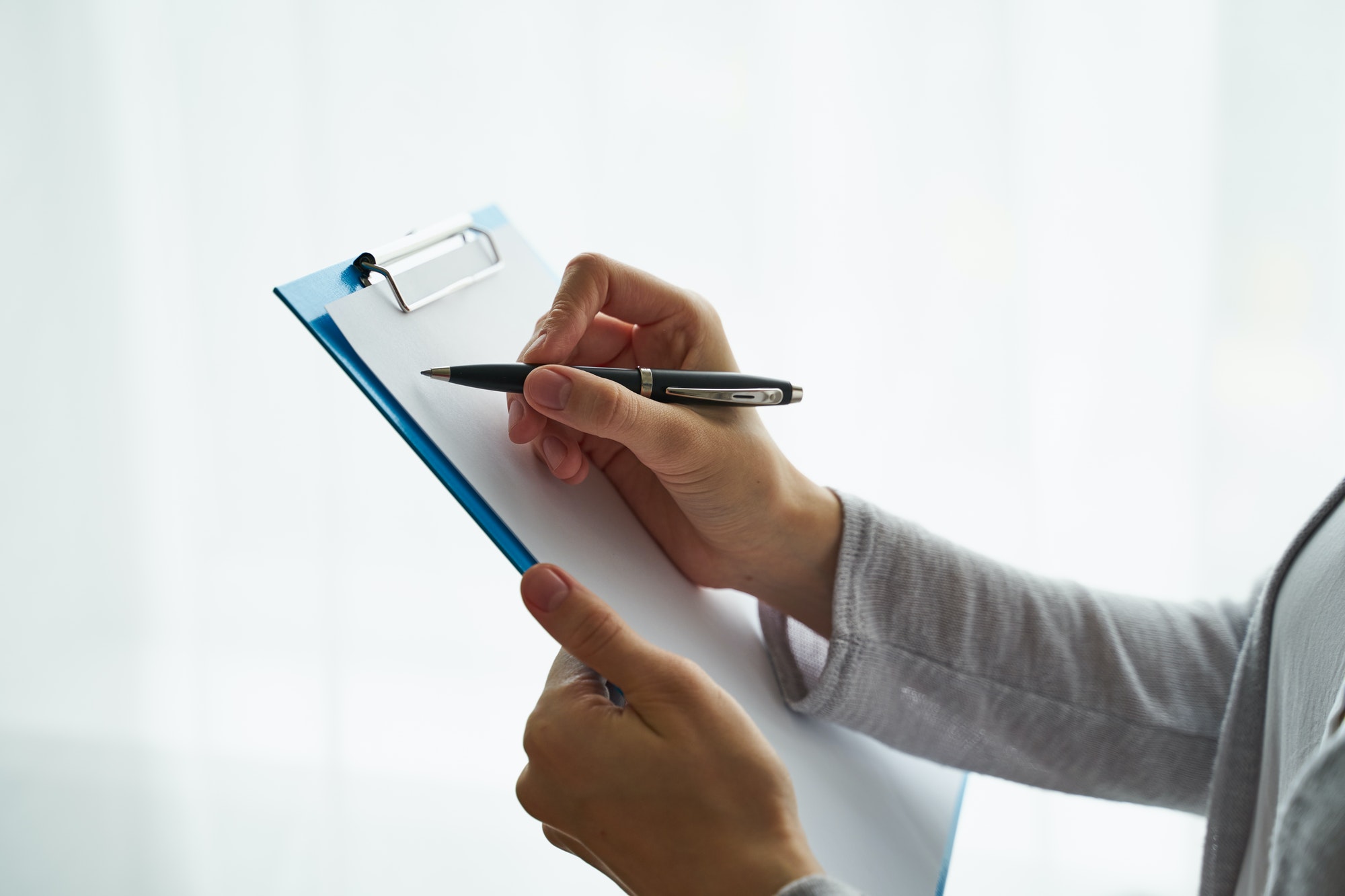 Unrecognizable person writing on clipboard, copy space